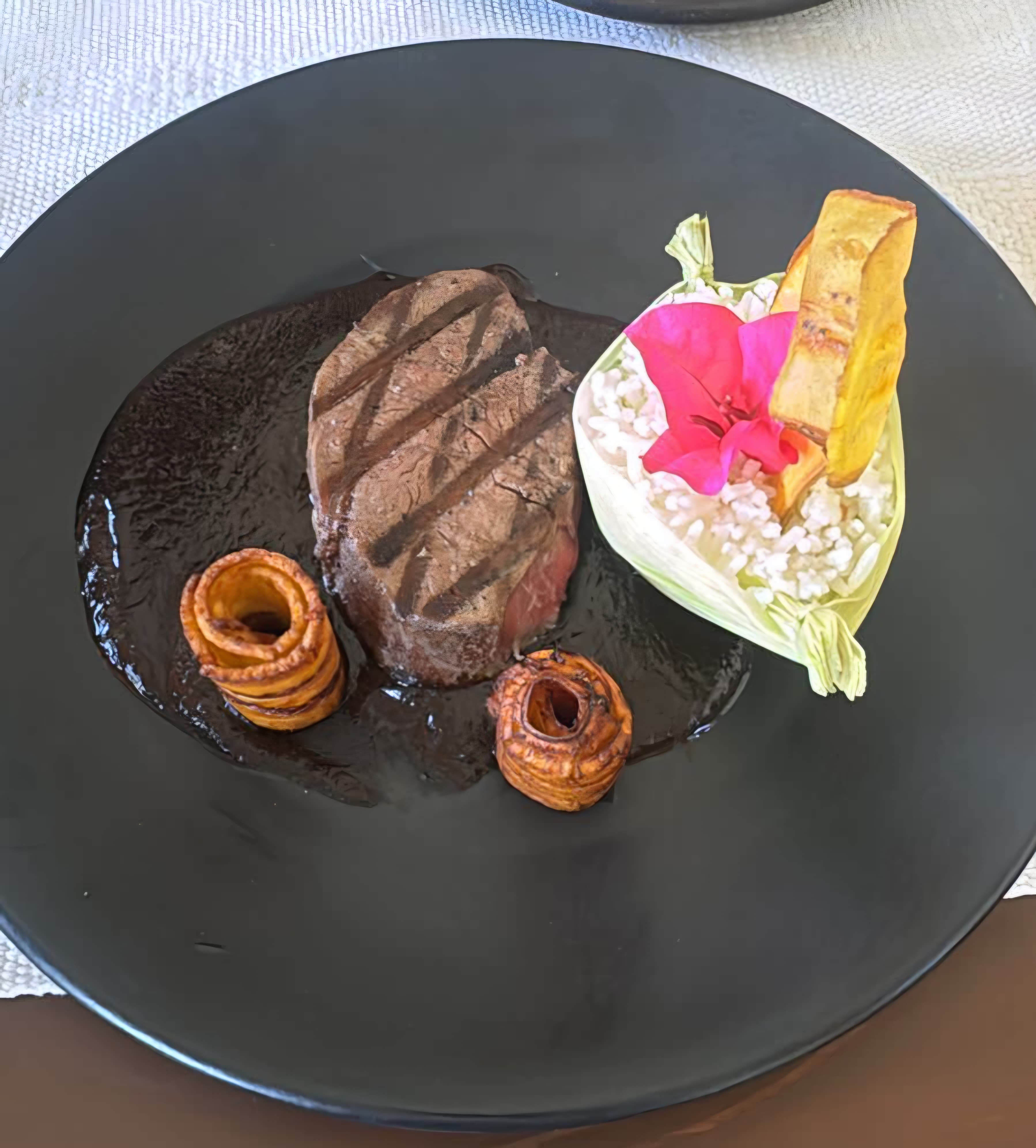 Beef tenderloin medallion served with Oaxaca black mole, white rice, and fried plantain spirals.